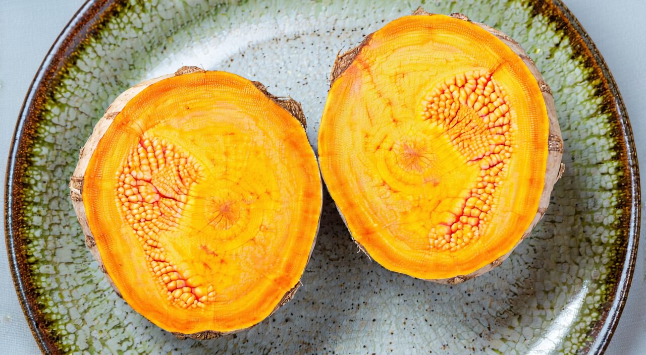 Close-up of a turmeric slice cross-section, showing the vivid orange-yellow cut surface
