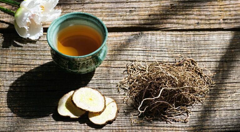 Close-up of natural white peony root and honey-fried licorice root with a cup of herbal tea, in natural light and a tranquil setting